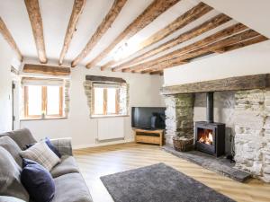 a living room with a stone fireplace and a tv at Hafotty Gelynen in Corwen