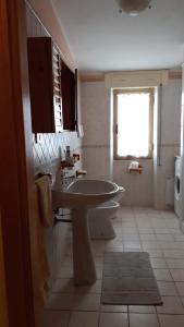 a white bathroom with a sink and a window at Casa Lucia Relax in Cala Gonone