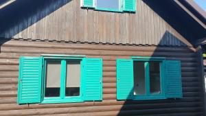 2 ventanas con persianas azules en un edificio de madera en Apartmaji sanje, en Brežice