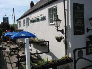 um edifício com guarda-sol, mesas e cadeiras em The Haymaker Inn em Chard