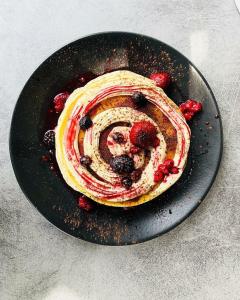 a pancake with berries on a black plate at BLACKHAUS Apartments in Thessaloniki