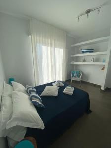 - une chambre avec un lit bleu avec des oreillers et une fenêtre dans l'établissement Il Veliero, à Polignano a Mare