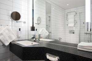 a white bathroom with a sink and a mirror at Scandic Meyergården in Mo i Rana