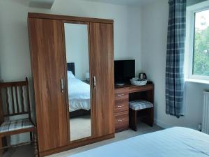 a bedroom with a wooden cabinet with a mirror at Snoozefrome in Frome