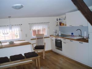 a kitchen with white cabinets and a chair and a sink at Stadtferienwohnung in Teterow