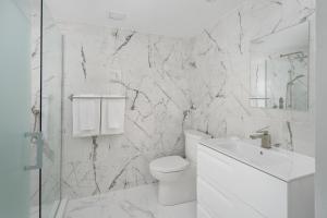 a white bathroom with a toilet and a sink at Sonder Saint Paul in Montreal