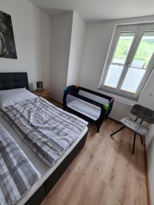 ein Schlafzimmer mit einem Bett und einem Stuhl sowie zwei Fenstern in der Unterkunft Ferienhaus Birute in Bernkastel-Kues