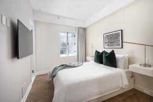 a white bedroom with a bed and a tv at Sonder Saint Paul in Montréal