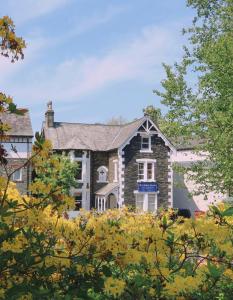 Rayrigg Villa at Windermere في ويندرمير: منزل من الطوب كبير مع الأشجار في المقدمة