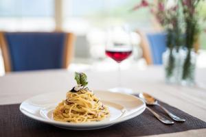 a plate of pasta on a table with a glass of wine at Ebnerhof in Appiano sulla Strada del Vino