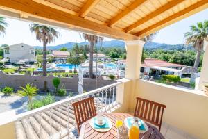 a balcony with a table and chairs and palm trees at Angelina Apartments in Roda