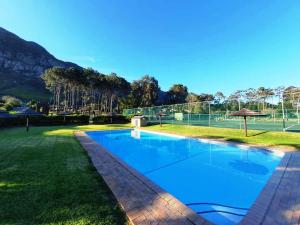 a swimming pool in a yard with a tennis court at Lagoon Edge in Hermanus
