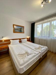 ein großes weißes Bett in einem Schlafzimmer mit Fenster in der Unterkunft Edelweiss Central Hotel in Bansko + 44 Fotos