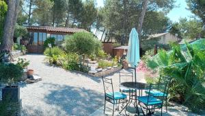 eine Terrasse mit einem Tisch, Stühlen und einem Sonnenschirm in der Unterkunft Les coronilles in Beaucaire