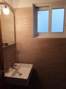 baño con lavabo y ventana en Alexandra rooms, en Skala Potamias