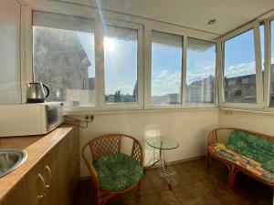 a kitchen with two chairs and a table and windows at Central Apartments in Odesa