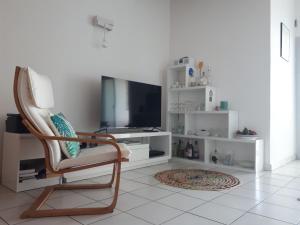 een woonkamer met een stoel en een televisie bij Apt spacieux 70m2 vue Océan, Piscine, Parking in La Saline les Bains
