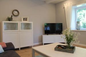 a living room with a flat screen tv and a table at Ferienwohnung Landfein in Quarnstedt