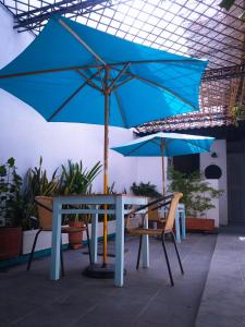 a table and chairs with a blue umbrella on a patio at Hostal Españolete in Santa Marta
