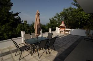 a patio with a table and chairs and an umbrella at L & A - GUEST HOUSE in Skala Potamias