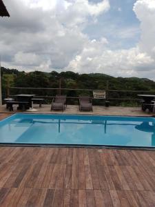 a pool with chairs and a picnic table on a deck at Pousada Só Alegria in Mario Campos