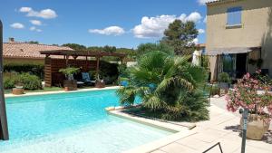 a swimming pool with a gazebo next to a house at Les coronilles in Beaucaire