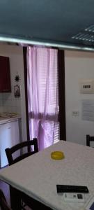a table and chairs in a kitchen with a pink curtain at Villa Lucia in Lampedusa