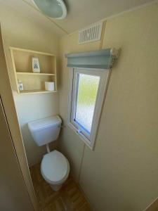 a small bathroom with a toilet and a window at Esmeralda's Caravan Hire Mablethorpe in Mablethorpe