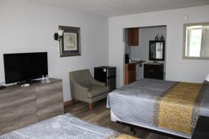 1 dormitorio con 1 cama, TV y silla en ANS INN & SUITES, en Winchester