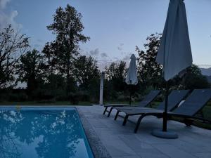 a swimming pool with two chairs and an umbrella at Villa Maraldo 1927 in Orgnese