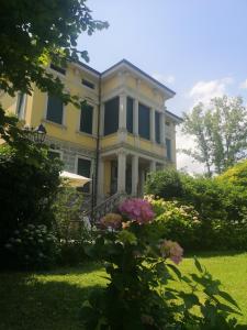 ein großes gelbes Haus mit Blumen im Hof in der Unterkunft Villa Maraldo 1927 in Orgnese