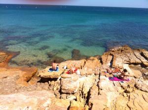 a group of people sitting on rocks near the water at Vilamar in Luz