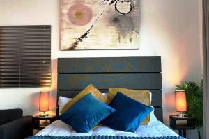 a bedroom with a bed with blue pillows at Relax,Revive,Reset & enjoy the sounds of the sea! in Cape Town