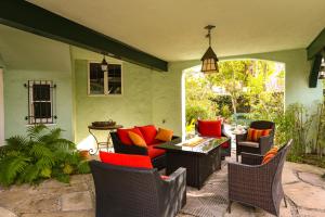 a patio with wicker chairs and a table with red pillows at Beautiful airy architect-designed room and brand new private luxe bathroom in Los Angeles