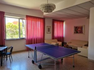 mesa de ping pong en la sala de estar con cortinas rojas en Hotel La Terrazza, en Porto San Giorgio