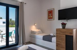Schlafzimmer mit einem Bett, einem TV und einem Balkon in der Unterkunft Liostasi Houses in Skyros