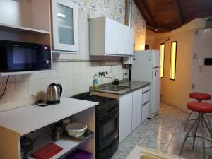 uma pequena cozinha com um fogão e um frigorífico em Comoda casa en el centro de Villa Carlos Paz, pileta privada, cinco minutos a pie de la peatonal, aire, porton electrico em Villa Carlos Paz