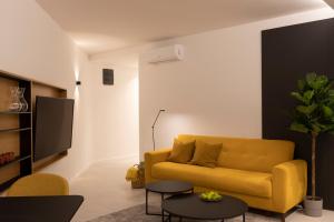 een woonkamer met een gele bank en een tv bij Apartman Mali raj in Pakoštane