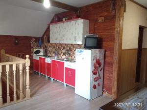 a kitchen with red cabinets and a white refrigerator at У Марка in Volosyanka