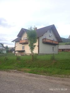 Una casa blanca con un árbol delante. en У Марка, en Volosyanka