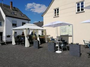 a patio with two white umbrellas and tables and chairs at Enscher Stübchen Wohnung Katharina in Ensch