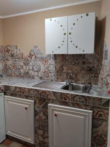 a kitchen with white cabinets and a sink at Il Vano della Scimmia Aeroporto Catania in Catania