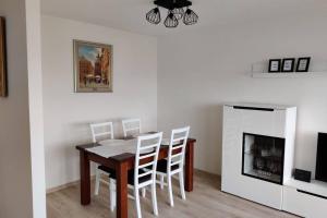 a dining room table with white chairs and a fireplace at Apartament Na 8 Piętrze in Płock
