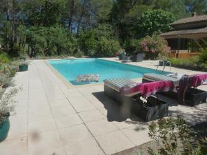 a swimming pool with two benches in a yard at Villa Les Oliviers in Draguignan