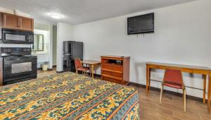 a hotel room with a bed and a desk and a television at Studios and Suites 4 Less Emporia in Emporia