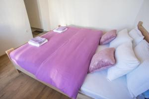 a bed with a purple blanket on top of it at Apartmani ALBION in Žabljak