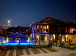 a house with a swimming pool at night at Pousada Villa Prainha in Farol de Santa Marta