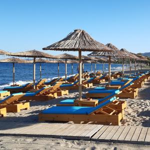 una fila di sedie a sdraio e ombrelloni in spiaggia di Studio Anlia a Nea Makri
