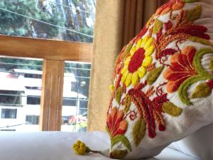 a pillow on a bed with a flower pattern on it at USGAR Machupicchu Boutique in Machu Picchu