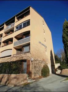 a tall brick building with a balcony on it at Studio Meublé Cures thermales avec vue in Gréoux-les-Bains